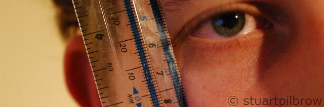 Person measuring eye with ruler