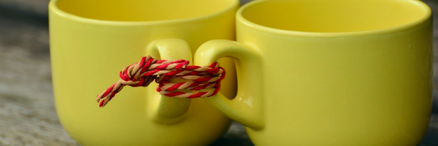 two yellow tea cups tied together with a red knot