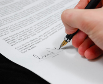 Right hand holding a pen while signing a portuguese contract
