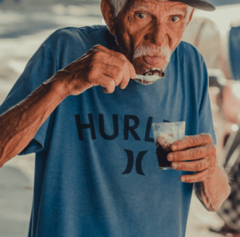 Old man in tshirt eating a desert in a cup