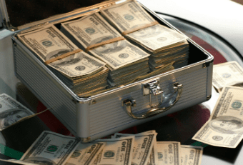 Briefcase full of dollar bills surrounded also by scattered dollar bills
